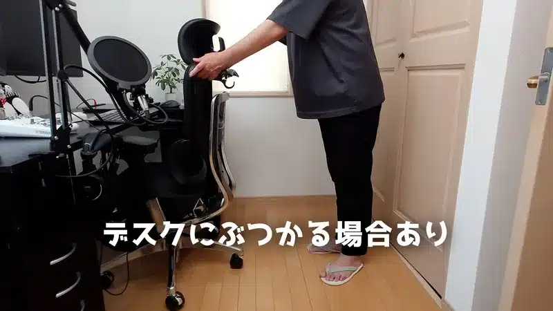 男性がCOFO Chair Premiumをデスク下に収納しようとした際、アームレストが天板にぶつかる様子。