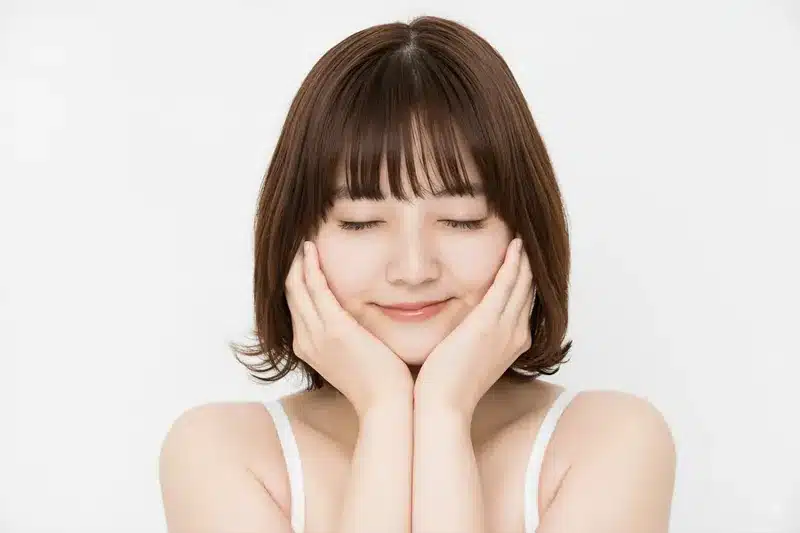 Nanobananaのプロンプトでポーズ変更を試す、目を閉じて頬に手をあて微笑むボブヘアの女性。