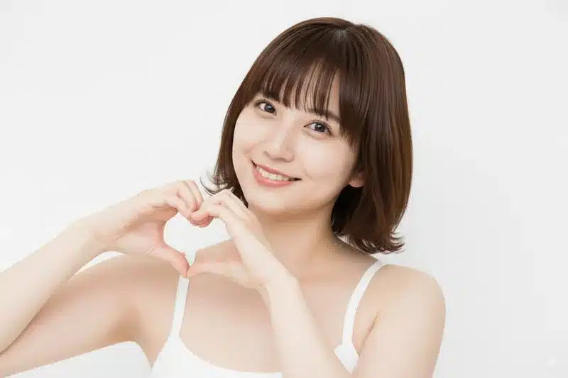 Nanobananaのプロンプトで、微笑む女性が両手でハートマークを作るポーズに変更した様子。