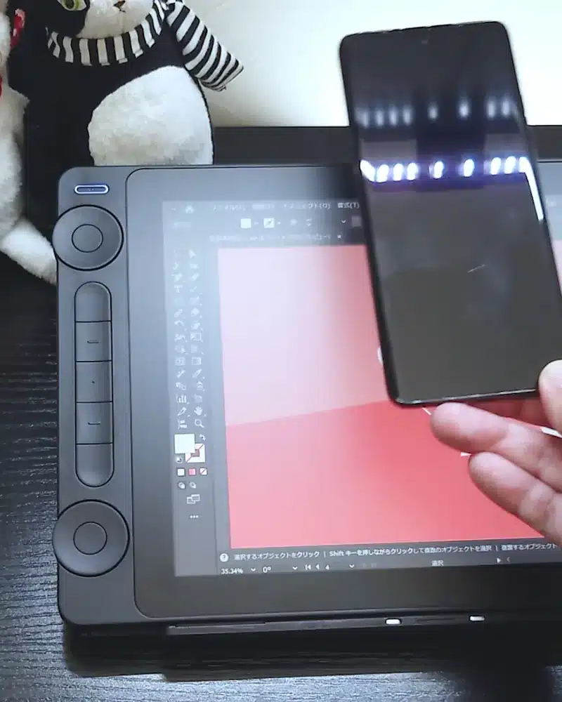 Huion Kamvas 13 (Gen3)の画面にスマートフォンをかざし、操作性を試している様子。